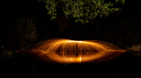 long exposure with sparks of steel wool on a stream of water and reflectionsの写真素材