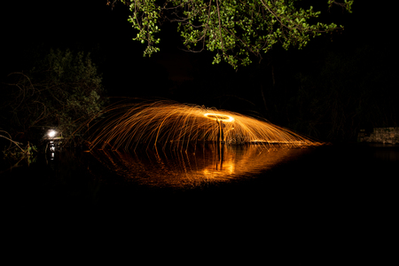 long exposure with sparks of steel wool on a stream of water and reflectionsの写真素材