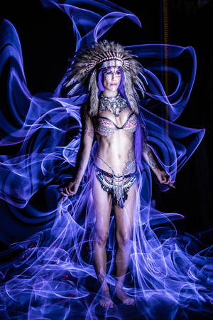 Woman dressed as an Indian poses as a model amidst long exposure lightsの写真素材