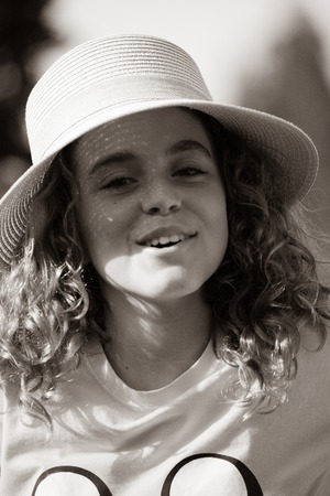 Close-up of a 10-year-old girl with a pamela in the garden of her houseの写真素材