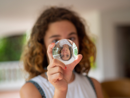 Portrait of a 10 year old girl, blonde and with curls looking at a crystal ball