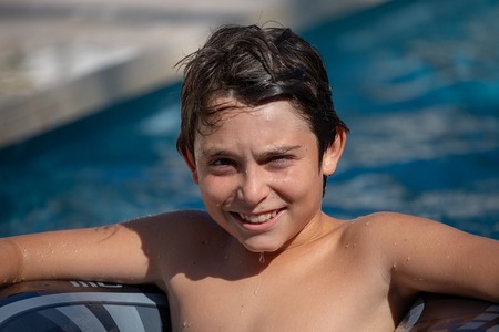 12 year old boy playing in the swimming pool of his house during the summer.の写真素材