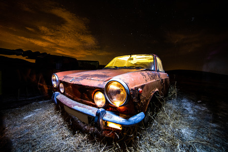 Ancient car abandoned in the countryside and illuminated with lanternsの写真素材