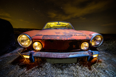 Ancient car abandoned in the countryside and illuminated with lanternsの写真素材