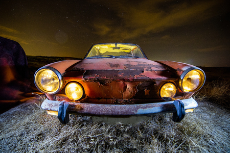 Ancient car abandoned in the countryside and illuminated with lanternsの写真素材