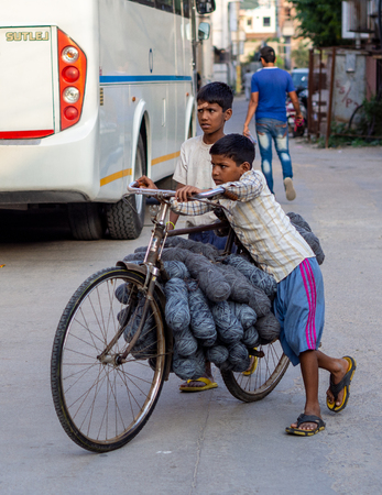 Jaipur, India, 18th to 22nd September 2018 Two children push a bicycle loaded with implements to develop their daily workのeditorial素材