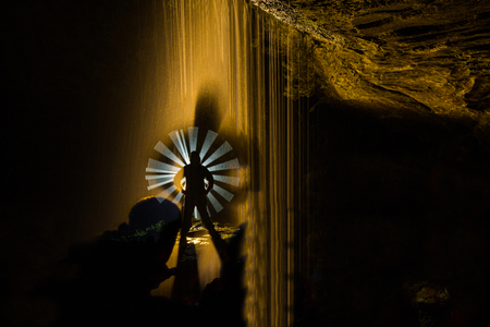 Night photograph inside a cave with waterfall and illuminated with coloured lanterns to highlight the figure of the model.の写真素材