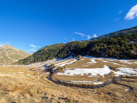 Photograph of a mountainous landscape on a sunny day in Andorra with a small rural houseの写真素材