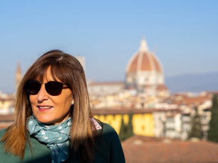 Mature and beautiful woman poses on a terrace and in front of the florentine cathedral, Santa Maria del Fiore y Ponte Vechioの写真素材