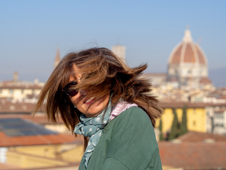 Mature and beautiful woman poses on a terrace and in front of the florentine cathedral, Santa Maria del Fiore y Ponte Vechioの写真素材
