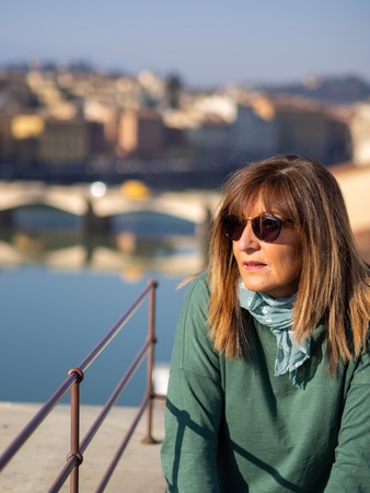 Mature and beautiful woman poses on a terrace and in front of the florentine cathedral, Santa Maria del Fiore y Ponte Vechioの写真素材