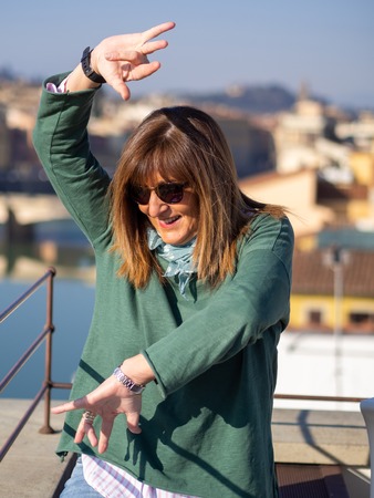 Mature and beautiful woman poses on a terrace and in front of the florentine cathedral, Santa Maria del Fiore y Ponte Vechioの写真素材