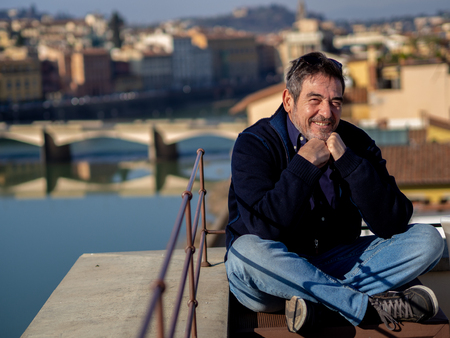 Mature man with a beard, posing seated in front of the ponte vechio in florence, Italyの写真素材