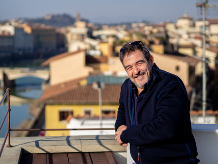 Mature man with a beard, posing seated in front of the ponte vechio in florence, Italyの写真素材