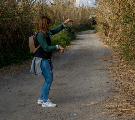 a 50-year-old woman plays in front of the camera and next to a high vegetation zone.の写真素材