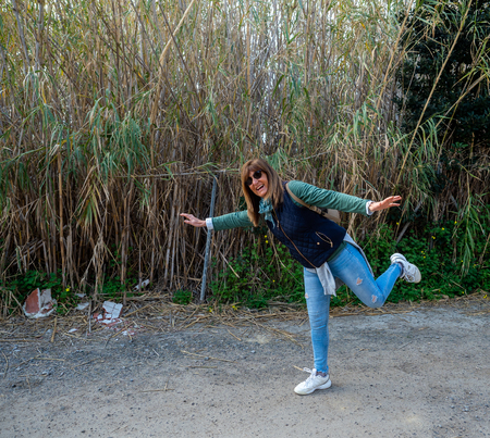 a 50-year-old woman plays in front of the camera and next to a high vegetation zone.の写真素材