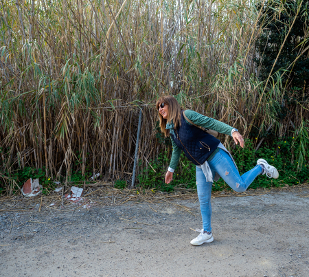 a 50-year-old woman plays in front of the camera and next to a high vegetation zone.の写真素材