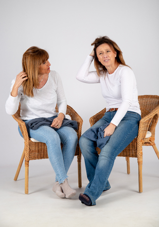 50 year old friends dressed in blue jeans and a white t-shirt laugh together playing with a blue scarf.の写真素材