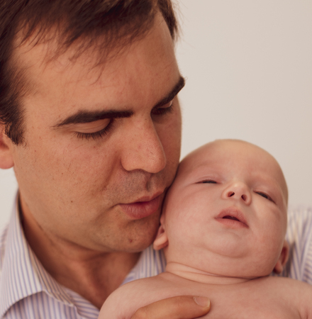Close-up of a father sleeping his baby in his arms in a photography studioの写真素材
