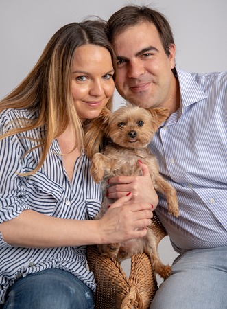 Young couple pose in a photography studio sitting in a chair with a yorkshire dog.の写真素材