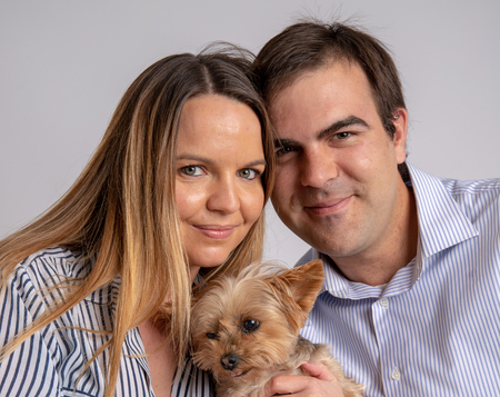Young couple pose in a photography studio sitting in a chair with a yorkshire dog.の写真素材