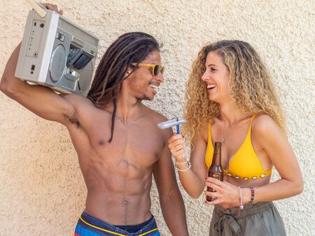 Caucasian blonde girl and black boy with dreadlocks, play with a cassette tapeの写真素材
