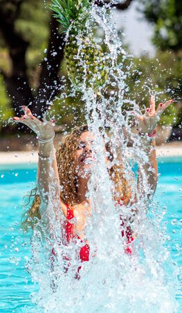 Caucasian blonde girl plays with a pineapple in the poolの写真素材