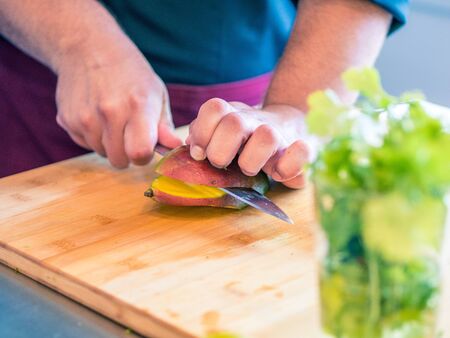 Close-up of man's hands preparing vegetables and fruit in modern cuisineの写真素材