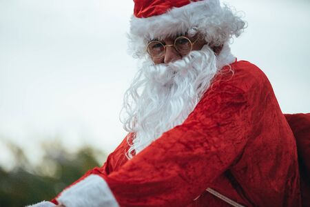 Stock photo of Santa Claus with gifts in the bicycle and his red suitcase on his back. Christmas...