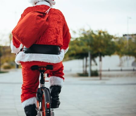 Stock photo of the view of Santa Claus' back with bicycle and his red suitcase on his back. Christmas timeの写真素材