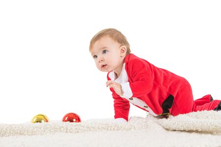 Stock studio photo with white background with a baby dressed as Santa playing with Christmas ballsの写真素材