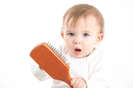 Stock studio photo with a white background of a baby with a comb in his handの写真素材