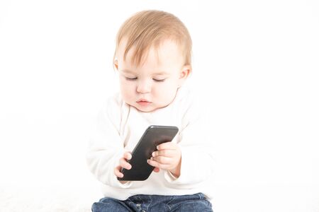 Stock studio photo with a white background of a baby with a mobile in his handの写真素材