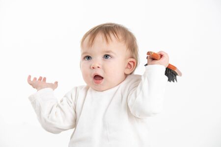 Stock studio photo with white background of a baby with arms raised with a toy in handの写真素材