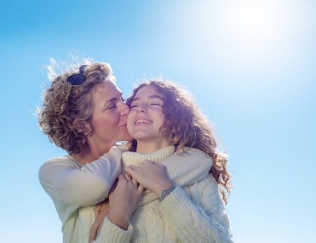 Young woman with her daughter in a very loving attitude. Burnt sky copy space