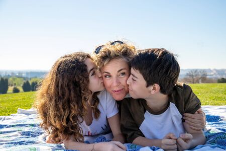 Family made up of a mother, son and daughter pose on a sunny day in a public park with a very affectionate attitude.の写真素材
