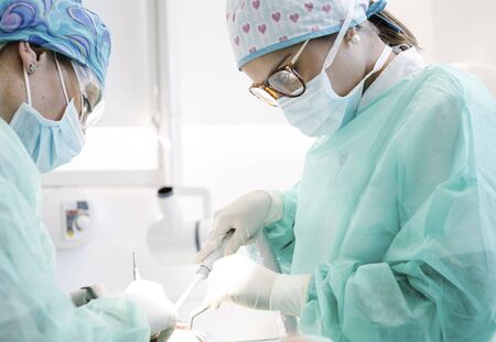 Women in masks and clean uniform performing healing procedure on patient while working in office in...