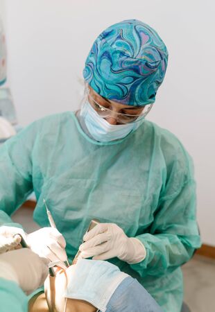 Dentist assistant inserts tool in patient's mouthの写真素材