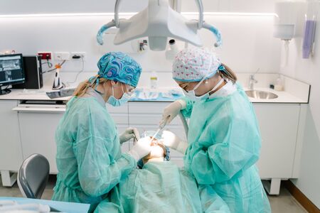 The assistant and the dentist talk to a patient during an operationの写真素材