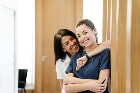 Two nurses laughing in the hallway of the clinic's officeの写真素材