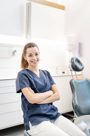 Young nurse in blue jacket smiles in the dental office before receiving the patientの写真素材