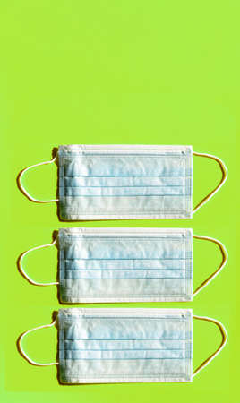 Group of three hygienic masks on a green colored background with free space. Vertical orientation