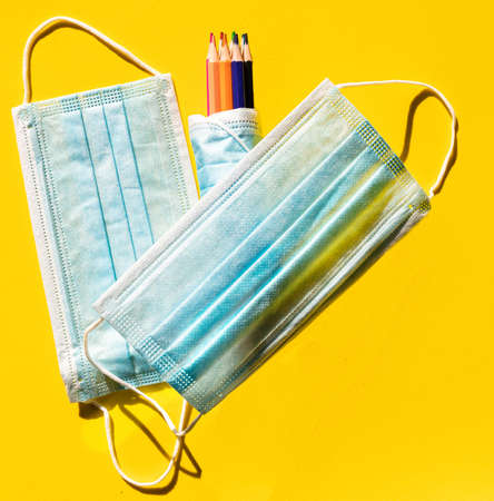 Set of colored pencils wrapped in a hygienic mask and surrounded by two other markers