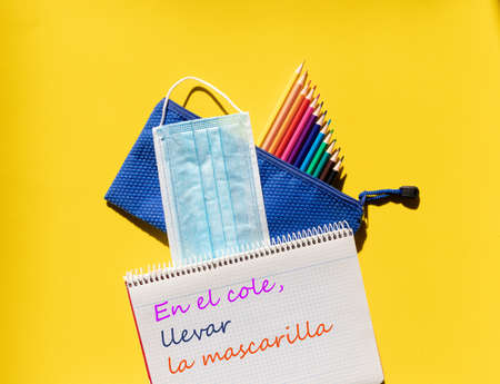 School notebook with legend, children's case, colored pencils, and mask against covid 19の写真素材