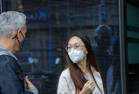Side view of company of friends in protective masks standing near showcase of shop and admiring goods during shopping in Madridの写真素材