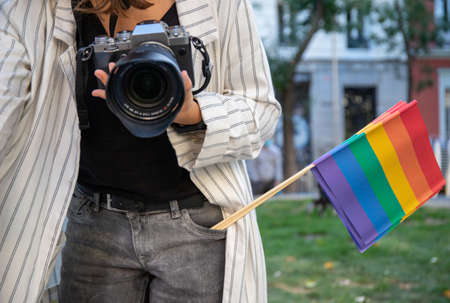 Crop unrecognizable female photographer with professional camera and LGBT rainbow flags standing in street of Madridの写真素材