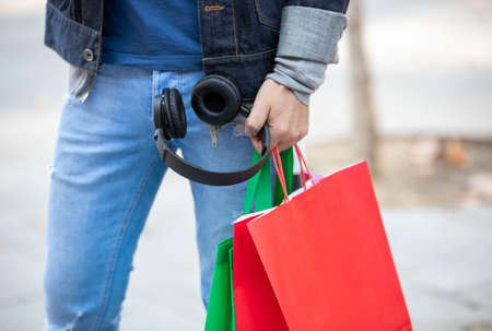 Unrecognizable stylish male in denim outfit standing with paper bags on street after shopping in Madridの写真素材