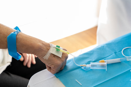 High angle of crop unrecognizable doctor with needle taking blood sample from senior female patientの写真素材