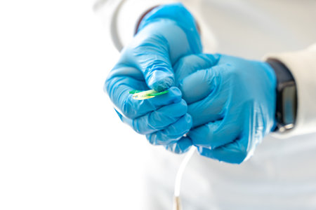 Crop anonymous medic in latex gloves and with needle for taking blood sample for coronavirusの写真素材