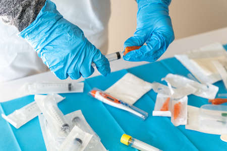 High angle of crop unrecognizable medic in latex gloves preparing syringe for injection in hospitalの写真素材